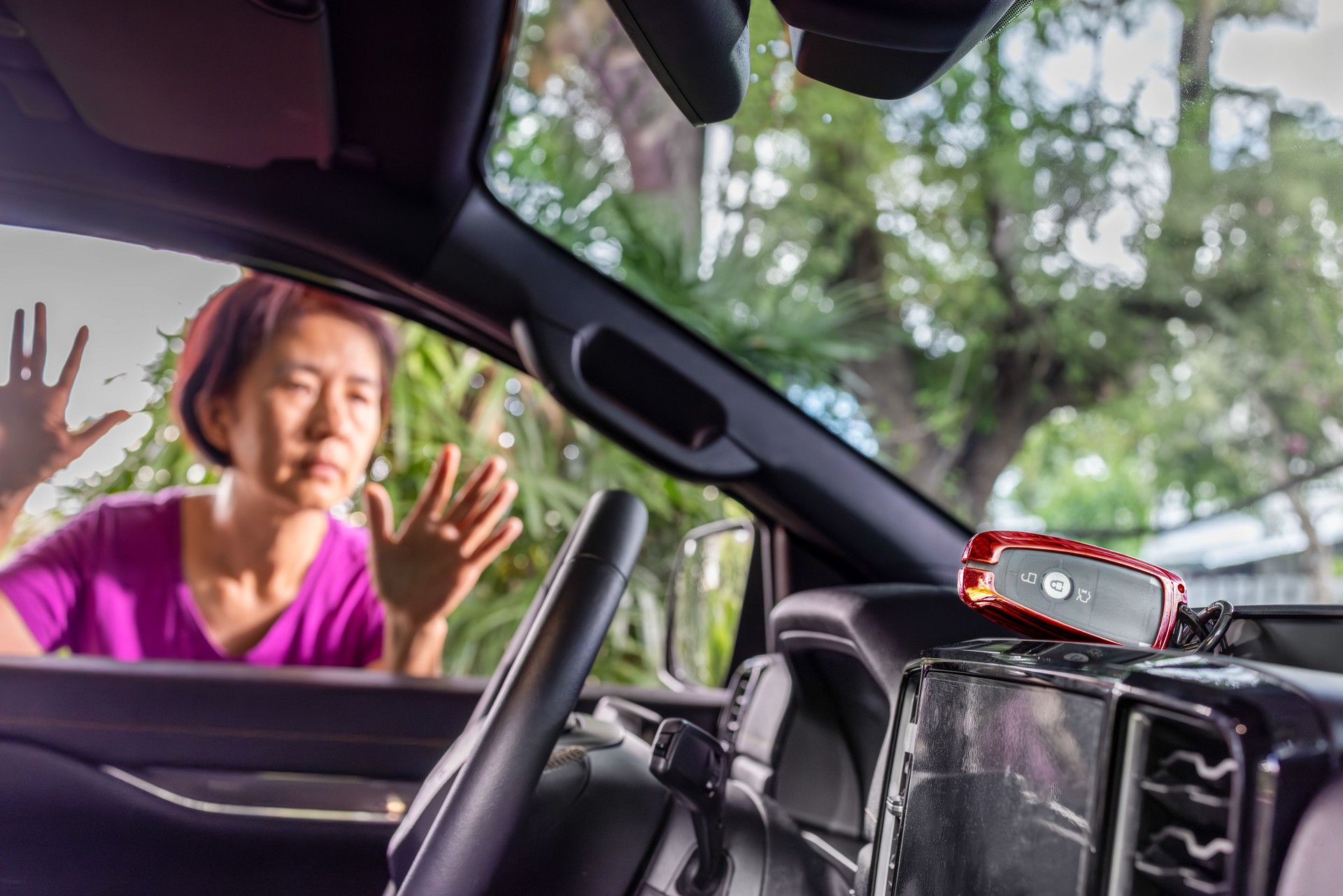 Senior asian woman forgot her key inside locked car.